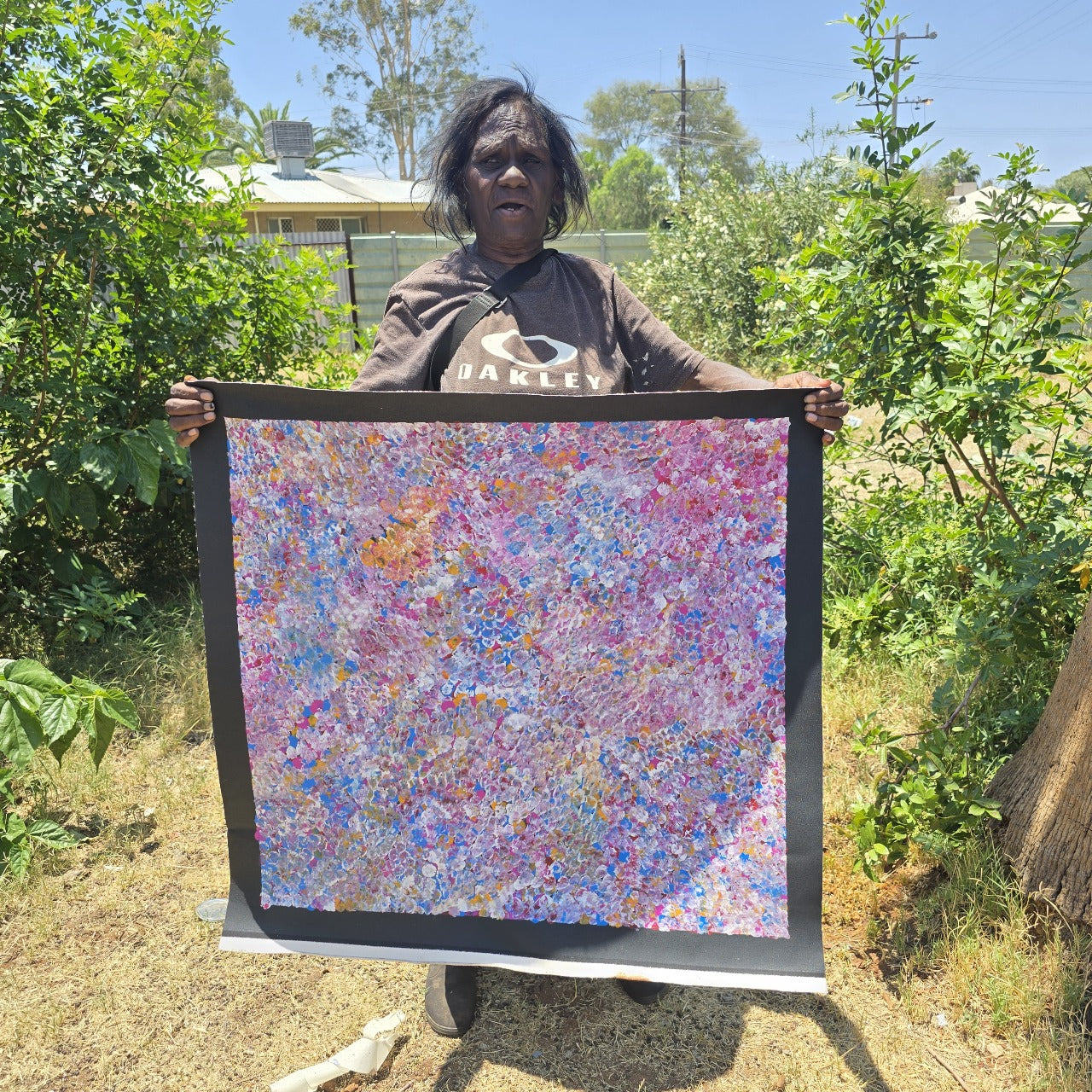 Bessie Pitjara holding an aborignal art of her own creation